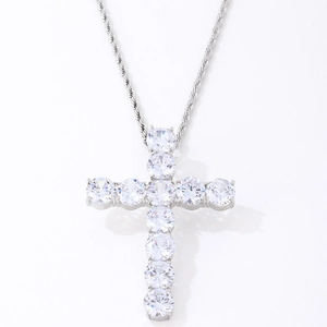 Gros plan d'un pendentif croix argenté avec de grosses pierres de zircon et chaîne torsadée