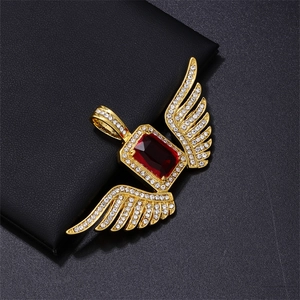 Macro shot of a gold hip hop wing pendant with a large red stone and micro-pave crystals