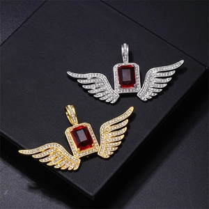Macro detail of iced-out wing pendants with red gemstone in gold and silver finish
