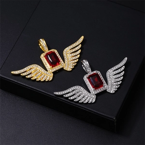 Macro shot of gold and silver angel wing pendants with red gemstone and white zircons