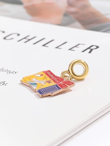 Macro detail of a colorful enamel boarding pass pendant with gold airplane engraving