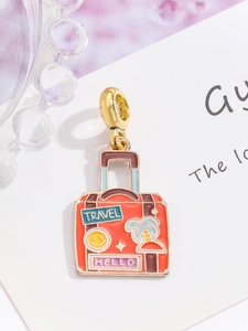 Close-up of orange enamel suitcase charm with gold TRAVEL and HELLO text for DIY bracelets
