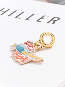Macro detail of a gold enamel airplane charm with Vacation text for travel bracelets