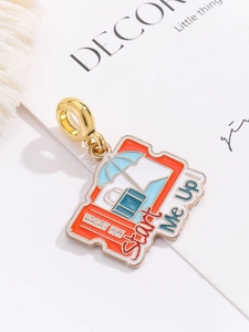 Detail of travel charm with blue suitcase and umbrella on gold enamel vacation bead
