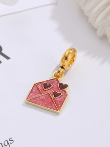 Makroaufnahme eines rosa glitzernden Umschlaganhängers mit kleinen roten Herzen für Schmuck
