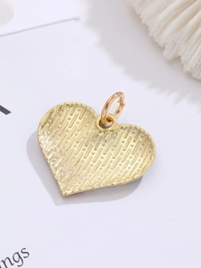 Macro shot of gold heart pendant back with textured finish and welded metal ring attachment