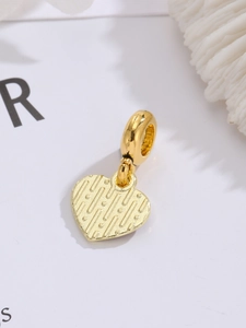 Makroaufnahme von Herzanhänger in Gold mit vertikalen Reliefstreifen für DIY-Schmuck