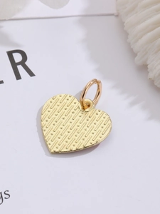 Detailed macro view of heart-shaped gold charm with textured surface and hanging loop