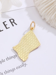 Macro detail of the golden metal heart pendant featuring a textured back and top loop