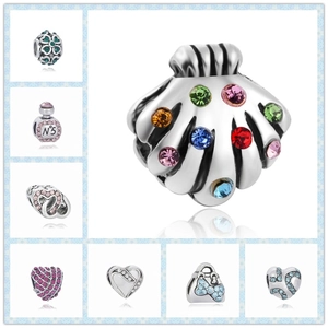 Detalle macro de dijes de plata S925 incluyendo corazones y frascos de perfume