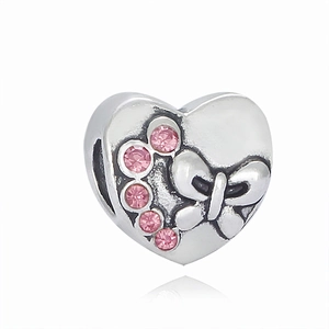 Macro view of silver heart bead with pink gemstones and carved butterfly detail