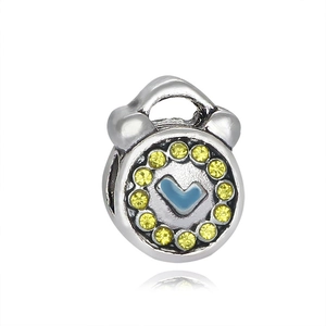 Macro detail of silver clock charm with yellow zircon inlay and blue enamel center