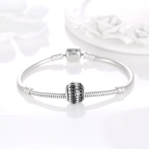 Detailed macro of a silver snake chain bracelet with black and white pavé barrel charms