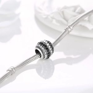 Macro shot of a silver charm bead with black and clear zircon stripes on a snake chain