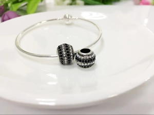 Detailed shot of silver open bangle with black and white crystal pave bead charms