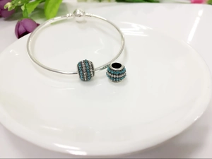 Macro detail of silver charm bracelet with blue and white pavé crystal ball beads