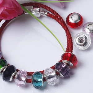 Close-up of candy-colored faceted glass beads on a red braided leather bracelet