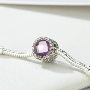 Dettaglio macro dello charm con gemma viola sfaccettata e intagli in argento