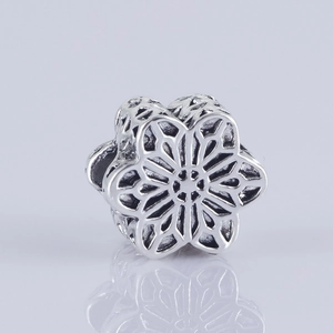 Detalle macro de cuenta espaciadora de flor hueca en plata antigua para joyería artesanal