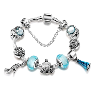 Détail d'un bracelet maille serpent argenté avec perles bleues et breloque carrosse