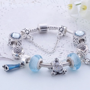 Détail de perles en verre bleu et breloques carrosse sur un bracelet perlé en argent