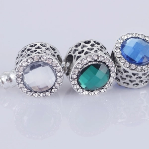Dettaglio macro di charm in argento con cuori traforati e cristalli colorati