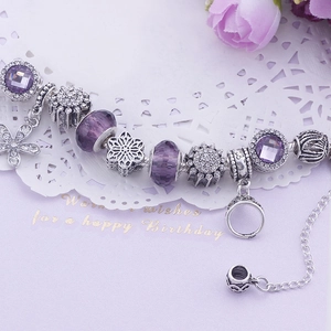 Détail d'un bracelet en perles violettes avec breloques flocon et perles de cristal élégantes