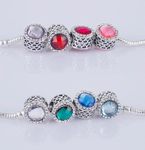 Vista dettagliata di charm a cuore in argento con gemme colorate e zirconi su catene snake