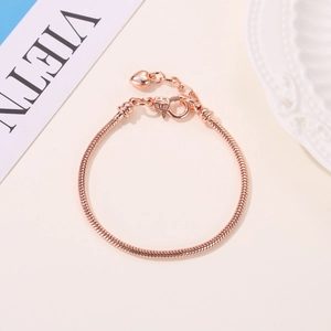 Gedetailleerd macro-aanzicht van een roségouden slangenarmband met hartbedel en kroonsluiting