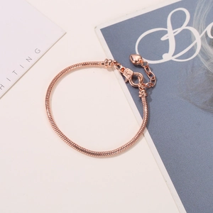 Detail van roségouden slangenketting armband met karabijnsluiting en hartvormige hanger
