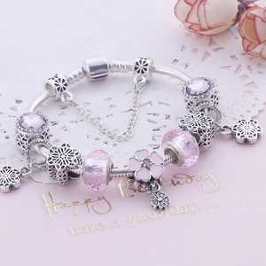 Detailed view of pink crystal glass beads and enamel floral charms on a silver snake chain
