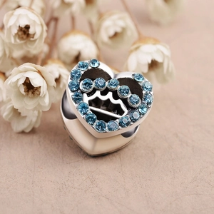 Detail of heart-shaped charm with blue zircons and crown cutout for DIY jewelry