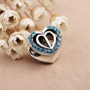 Macro view of heart-shaped silver charm with light blue crystals for DIY jewelry