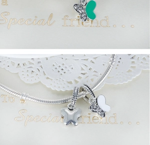 Detailed macro view of silver butterfly charm with green enamel and white zircon stones