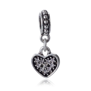 Macro shot of silver heart charm pendant with clear cubic zirconia stones and beaded ring
