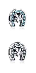 Macro shot of two silver horseshoe charms with star center and blue crystal inlays