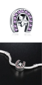 Macro view of silver horseshoe charm with purple zircon star on a snake chain bracelet