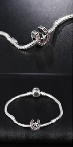 Detail of horseshoe charm with pink zircons and star on silver snake chain bracelet