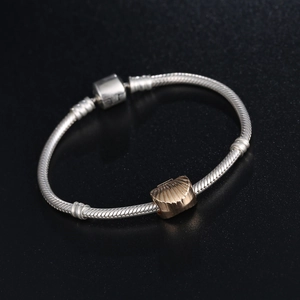 Silver snake chain bracelet featuring a gold shell charm and barrel clasp closure