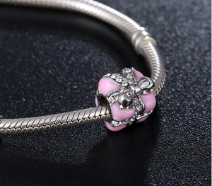 Detail of pink enamel gift box bead charm with zircon bow on silver snake chain