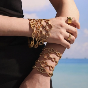 Bracelets dorés avec cœurs en zircon et maillons sur fond de plage ensoleillée