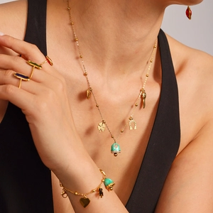 Golden luxury jewelry set with colorful enamel charms and gemstone rings on a model