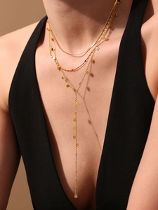 Detailed view of layered gold Y-necklace with polished disc pendants on a model