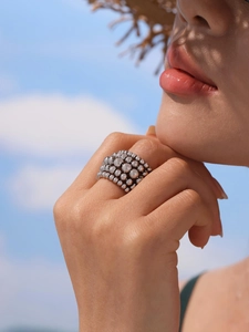 Macro shot of silver multi-layer beaded wide ring worn by model in outdoor sunlight