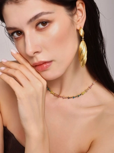 Macro shot of large textured golden teardrop earrings and a colorful gemstone necklace