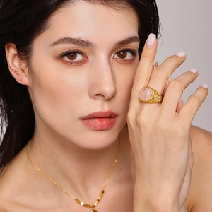 Elegant 18K gold plated ring with oval rose quartz stone worn by a model in soft light