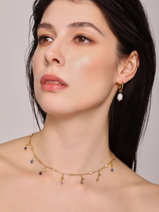 Gros plan sur collier en lapis-lazuli et boucles d'oreilles perles baroques portés