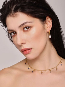 Gros plan d'un collier doré avec lapis-lazuli et zircons avec boucles d'oreilles perles