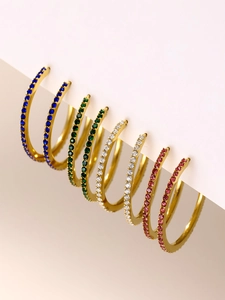 Macro shot of gold hoop earrings with colorful inlaid zircons on a white display card