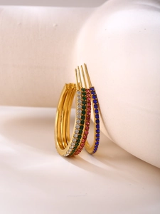 Detailed macro of gold U-shaped hoop earrings featuring colorful zircon inlay and stones